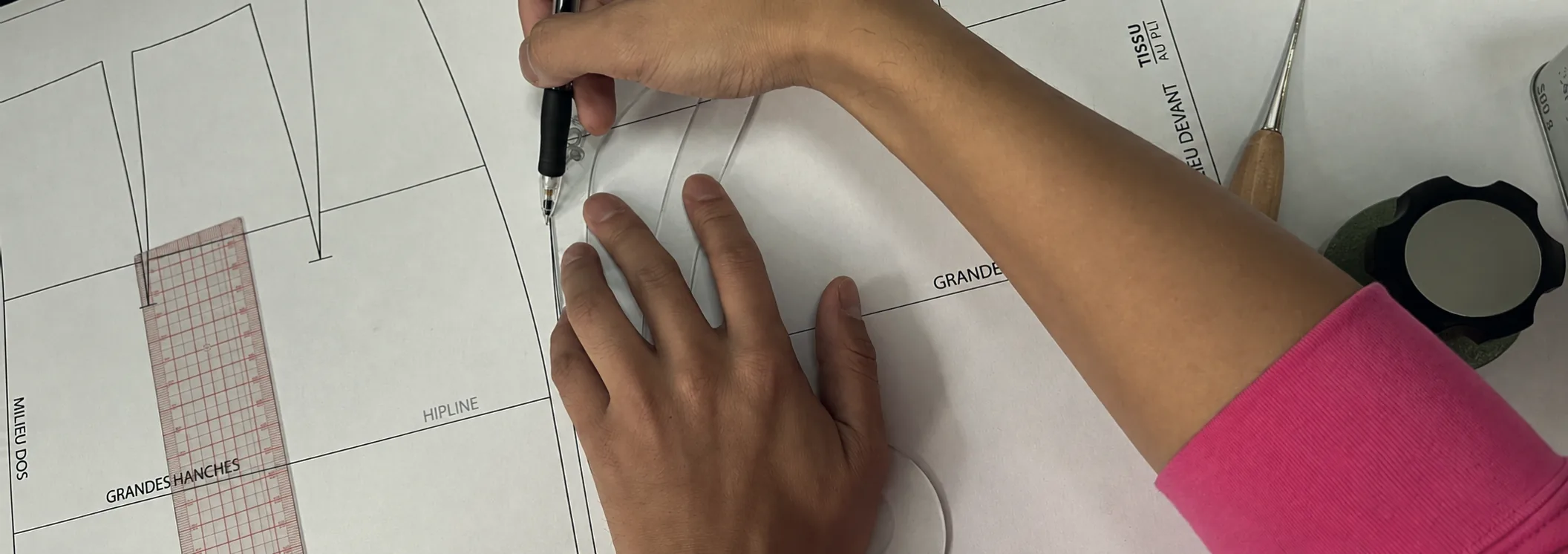 Une main trace au crayon sur un patron