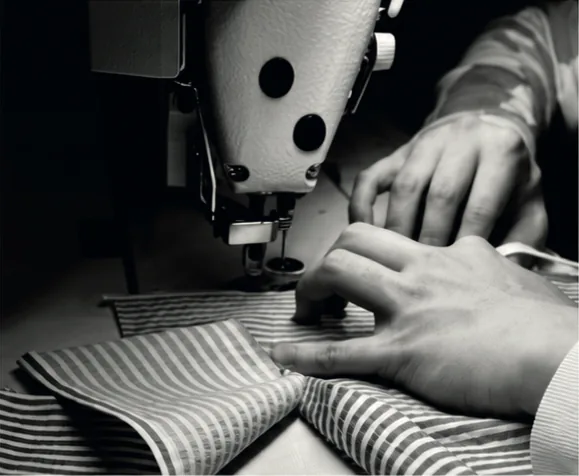 Des mains guident un tissu rayé sous la machine à coudre