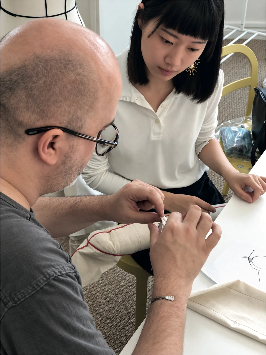 Dominique Pellen works on an ecru toile mannequin arm, next to an attentive student