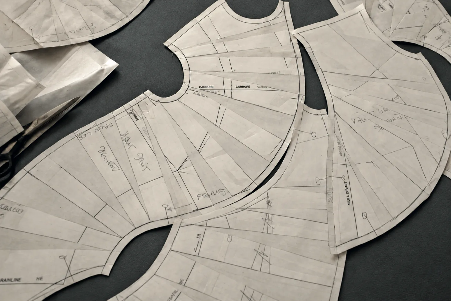 Cape pattern pieces cut and fanned out on a black background, with a pair of scissors