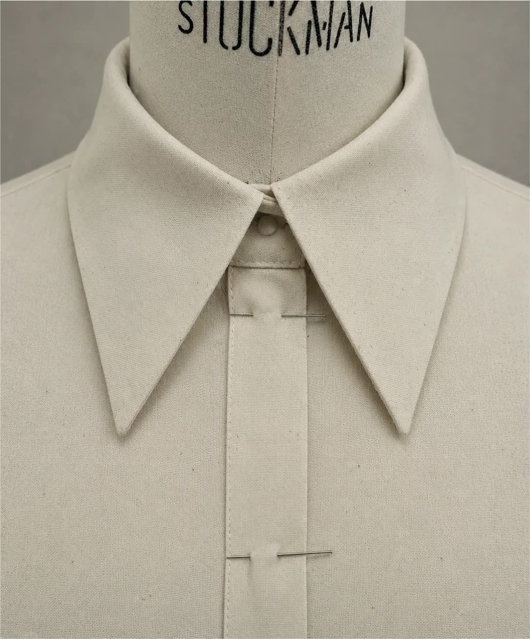 A pointed shirt collar in ecru calico, pinned on a Stockman dress form