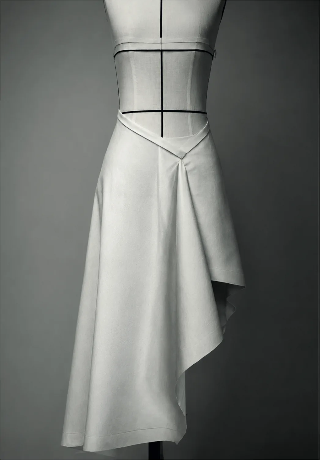 A white asymmetric skirt, draped at the side, on a dress form